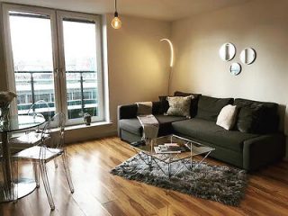 Chic, contemporary living room with a dark green sofa, mirrored coffee table, and modern art on the walls, bathed in natural light